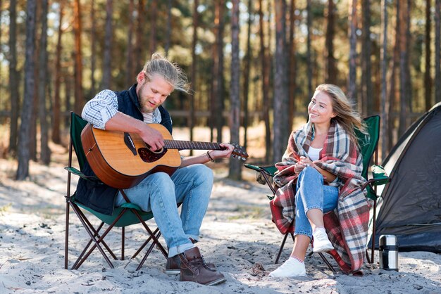 Freund spielt Akustikgitarre und sitzt auf Stuhl