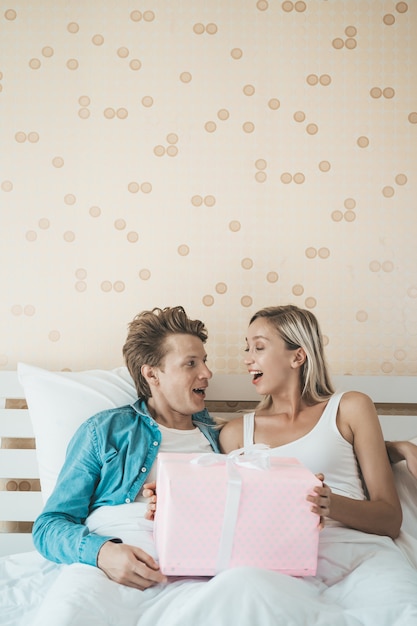 Freund überraschen seine Freundin mit Geschenkbox auf dem Bett