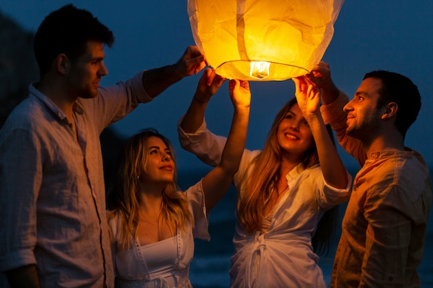 Freunde am Strand, die nachts Laterne starten