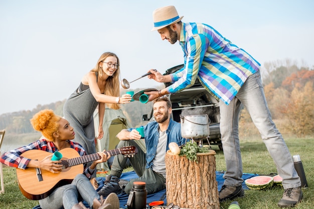 Freunde bei einem leckeren abendessen mit im kessel gekochter suppe während des picknicks auf dem campingplatz
