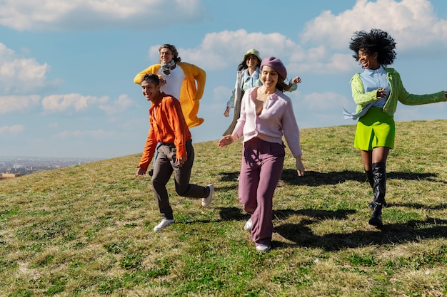 Kostenloses Foto freunde, die auf einem feld im freien den hügel hinunterlaufen