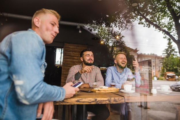 Kostenloses Foto freunde, die im restaurant gesehen vom fensterglas genießen