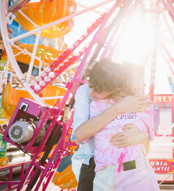 Freunde, die im Sonnenlicht am Funfair umarmen