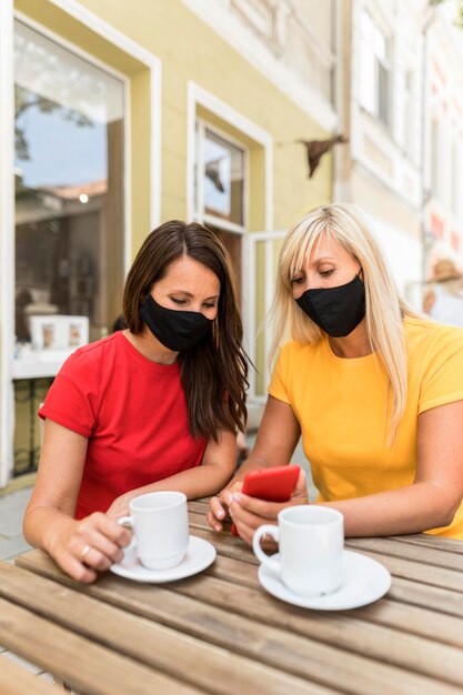 Freunde, die Masken tragen und einen Kaffee genießen