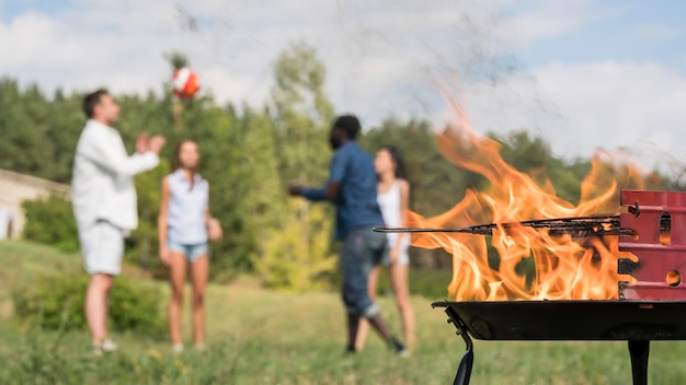 Kostenloses Foto freunde, die mit ball neben dem grillen spielen