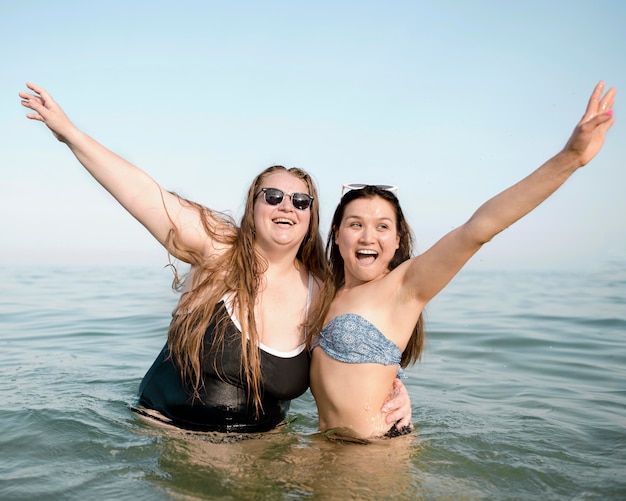 Kostenloses Foto freunde, die mit den händen in der luft im wasser stehen