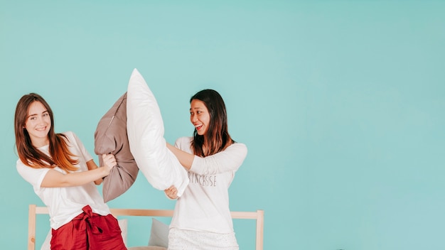 Freunde, die mit Kissen auf Bett kämpfen