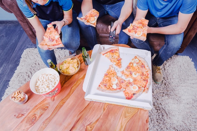 Freunde, die Pizza essen und Fußball aufpassen