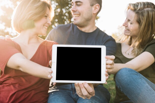 Freunde, die Tablette im Park zeigen