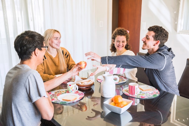 Freunde, die versuchen, Apfel von der Hand des Mannes beim Frühstück zu erhalten