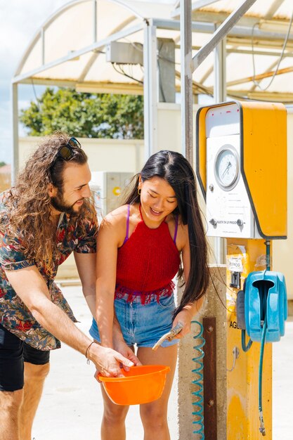 Freunde, die Wasser an der Tankstelle während des Zwischenstopps erhalten