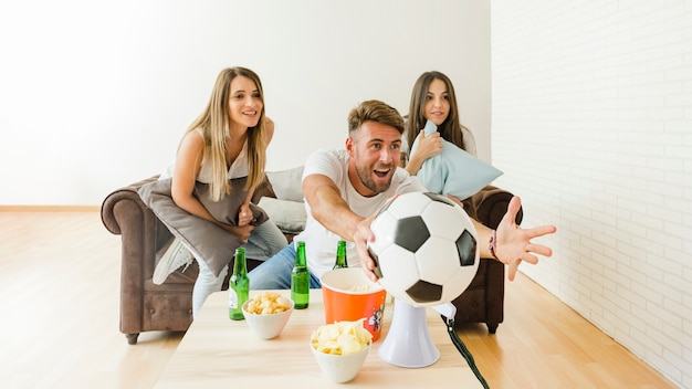 Freunde, die zu Hause Fußball aufpassen zujubeln