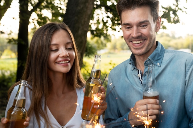 Freunde draußen im Park, die Bier trinken und Wunderkerzen genießen