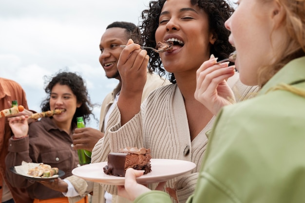 Freunde essen Grill und Kuchen während der Party im Freien