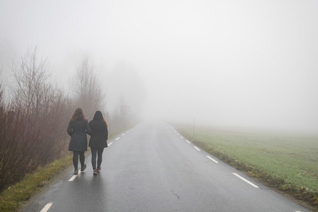 Freunde gehen eine Straße entlang, die zum Nebel führt