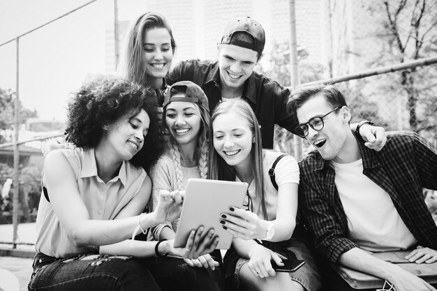 Freunde im Park unter Verwendung einer tausendjährigen und digitalen Tablette der digitalen Tablette