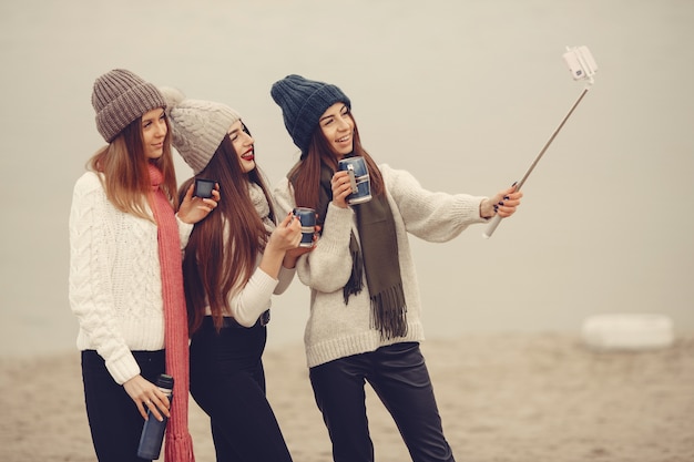 Freunde in einem Winterpark. Mädchen in Strickmützen. Frauen mit Thermoskanne und Tee.