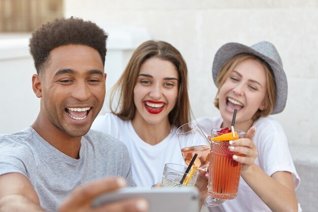 Freunde lächeln an der Kamera des Handys, während sie selfie nehmen