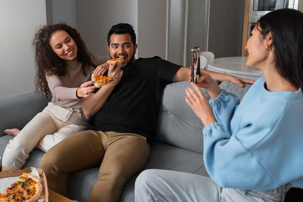 Freunde machen Fotos, während sie zu Hause Pizza essen