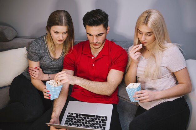 Freunde mit aufpassendem Film des Popcorns auf Laptop