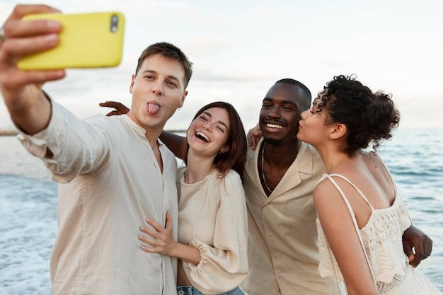 Freunde mit mittlerer aufnahme, die ein selfie am meer machen