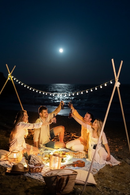 Freunde nachts am Strand mit Bier und Essen