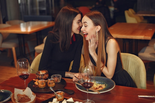 Freunde reden und haben Spaß bei der Dinnerparty. Elegant gekleidete Frauen von Menschen, die zu Abend essen.