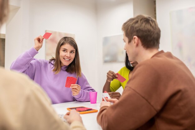 Freunde sitzen am Tisch und spielen Karten