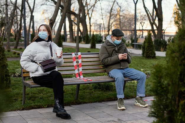 Freunde sitzen in der Ferne und tragen Maske