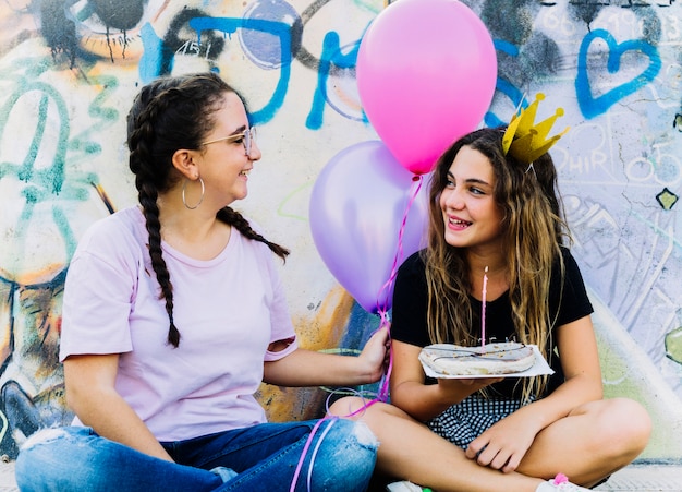 Freunde sitzen mit Luftballons und Geburtstagsgebäck