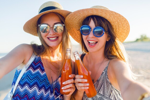 Freunde trinken Getränke in Flaschen am Strand