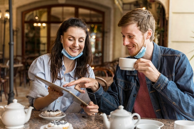 Kostenloses Foto freunde unterhalten sich im restaurant, während sie medizinische masken am kinn haben