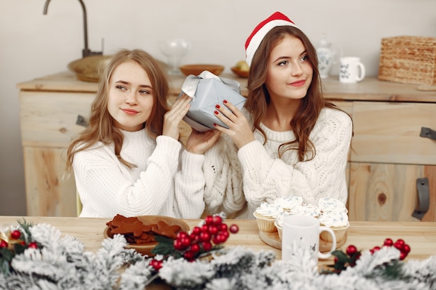 Freunde verbrachten Zeit zu Hause. Zwei Mädchen trinken Tee. Frau in einer Weihnachtsmütze.