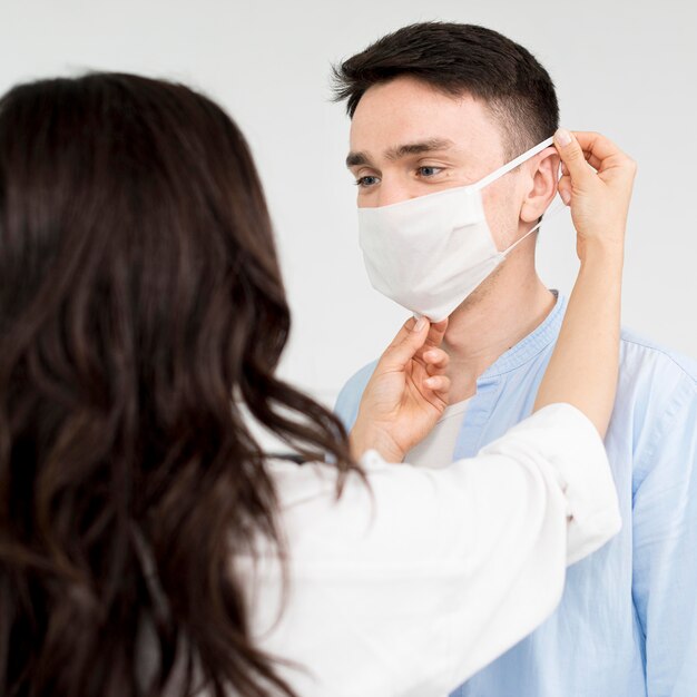 Freundin hilft Freund auf Gesichtsmaske setzen