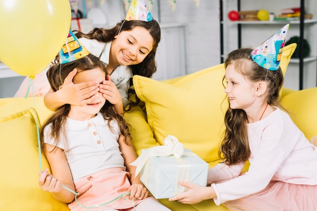 Freundinnen, die dem Geburtstagsmädchen zu Hause Geschenk geben