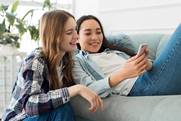 Freundinnen, die Handy schauend lächeln