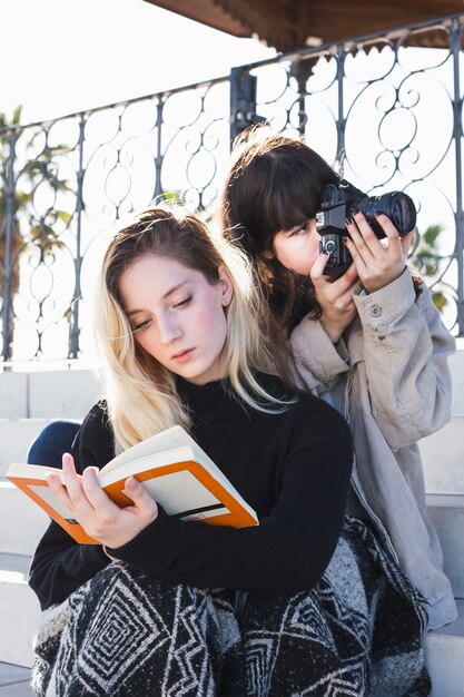 Freundinnen, die mit Buch und Kamera kühlen