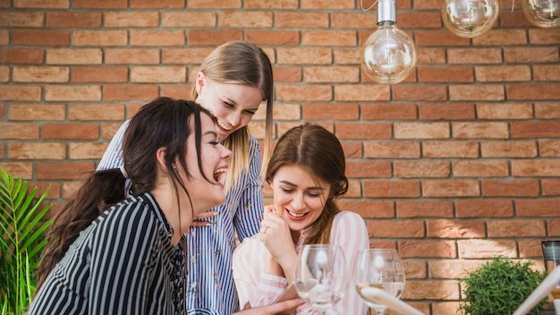 Freundinnen, die Smartphone und das Lachen betrachten