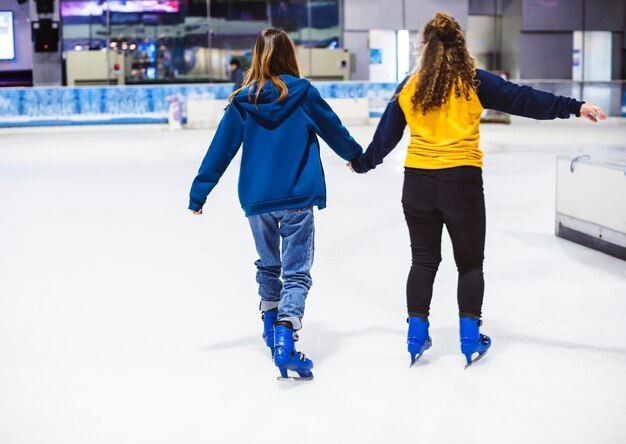 Freundinnen Eislaufen auf der Eisbahn zusammen