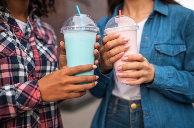 Freundinnen mit Milchshakes im Freien zusammen