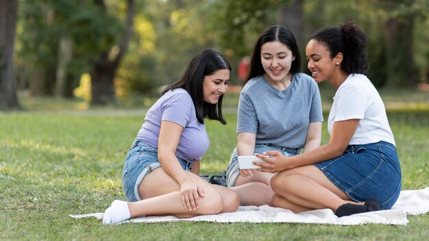 Freundinnen mit Smartphone zusammen im Park