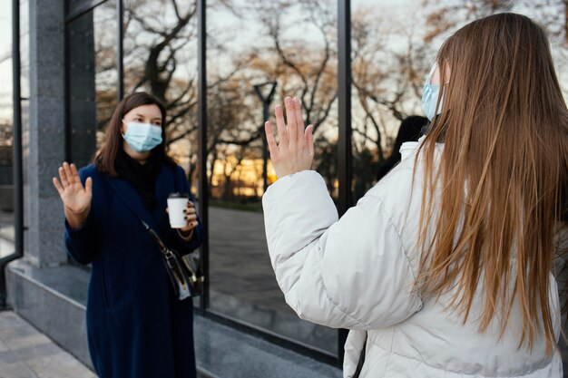 Freundinnen tragen Masken und winken