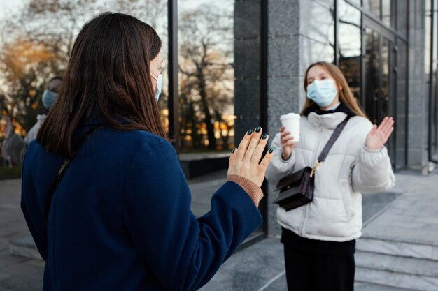 Freundinnen tragen Masken und winken