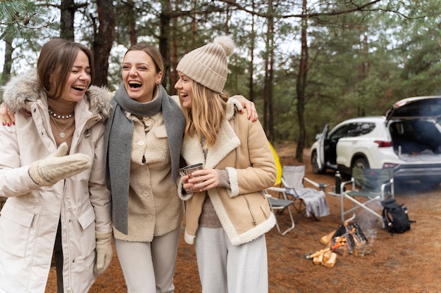 Freundinnen trinken Wasser und lachen beim Camping