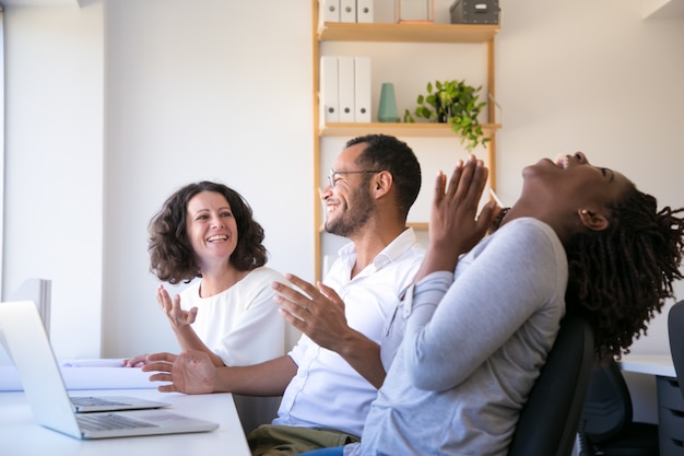 Freundliche Angestellte, die am Arbeitsplatz sprechen und lachen