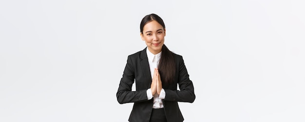 Freundliche asiatische Geschäftsfrau hält Händchen zusammen und verbeugt sich vor Geschäftspartnern, die z. B. Kunden begrüßen