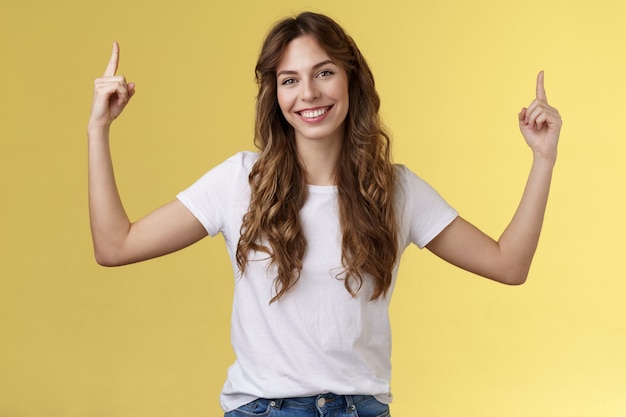 Freundliche, charismatische, gutaussehende Frau, die Ihnen einen großartigen Promo-Platz zeigt, der nach oben zeigt, Zeigefinger hebt ...