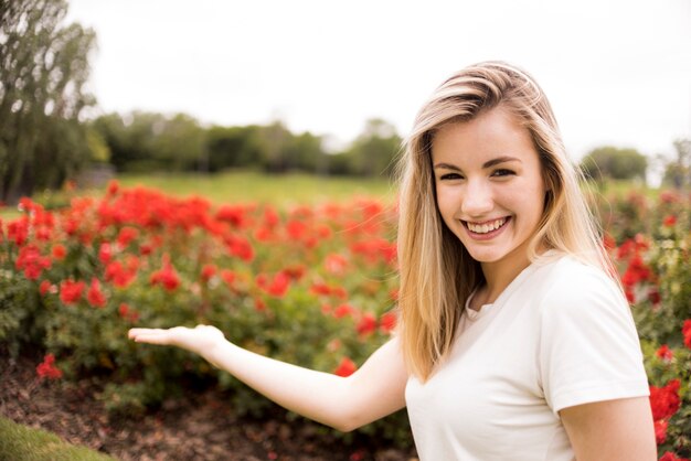 Freundliche Dame im T-Shirt nahe roter Blüte