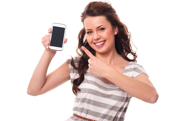 Freundliche Frau, die auf dem Bildschirm weißes Handy zeigt