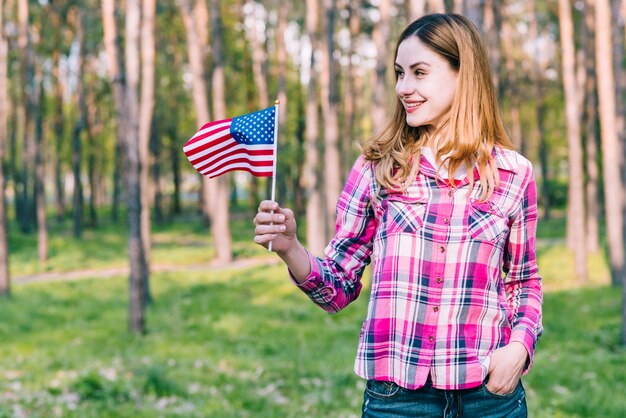 Freundliche Frau, die mit amerikanischer Flagge steht